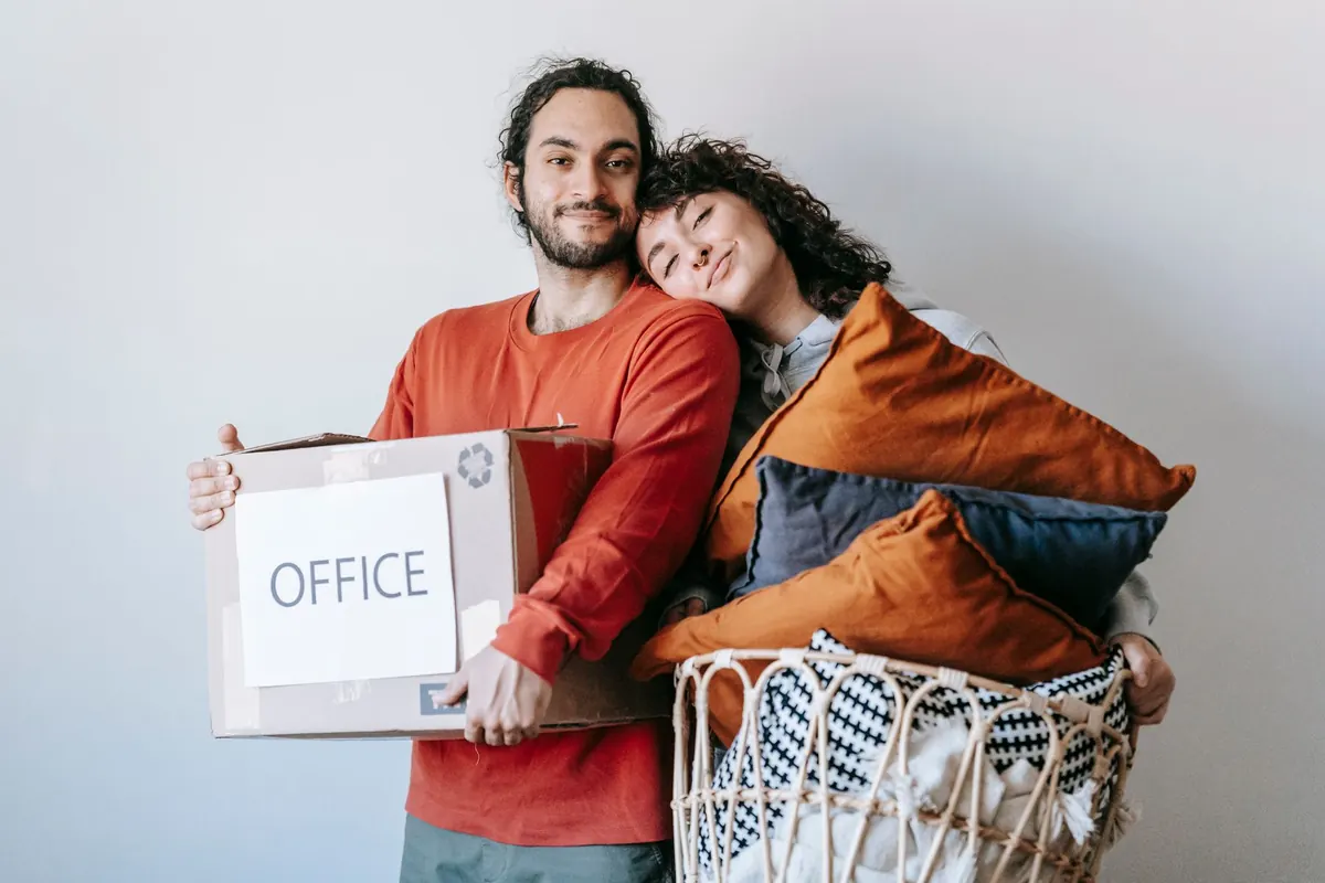 Ein Paar hält Kartons und Bürozubehör in einem Arbeitszimmer bereit