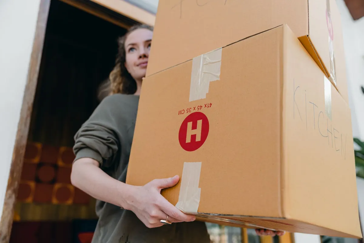 Eine Person trägt mehrere gepackte Kartons aus einer Wohnung