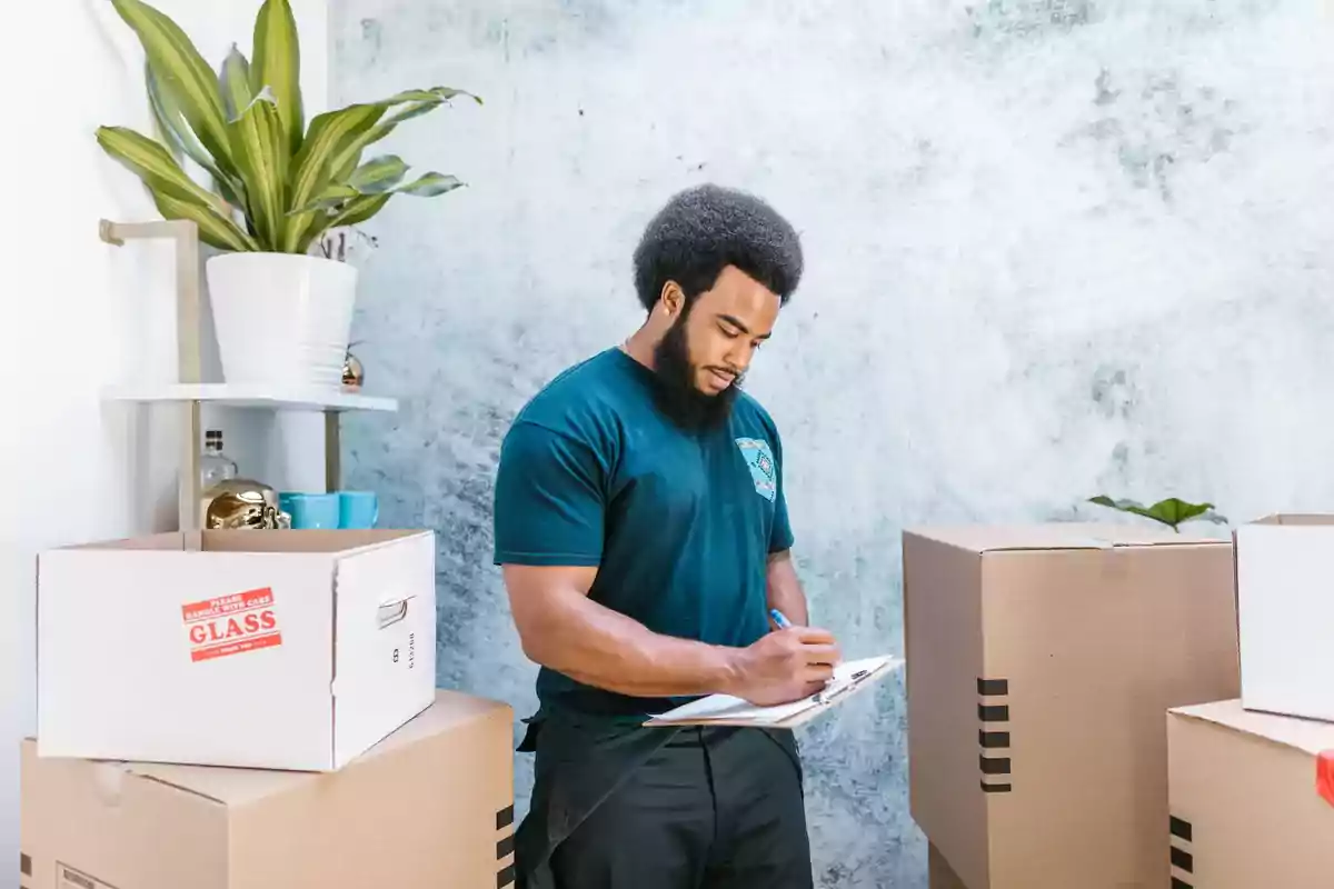 Ein Helfer prüft eine Liste zwischen gepackten Umzugskartons