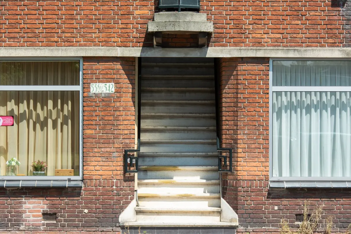 Der Eingang eines Mehrfamilienhauses liegt direkt an einer Wohnstraße