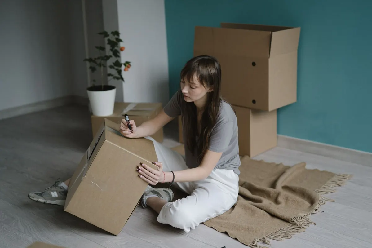 Eine Frau zählt gepackte Kartons in einem fast leeren Zimmer